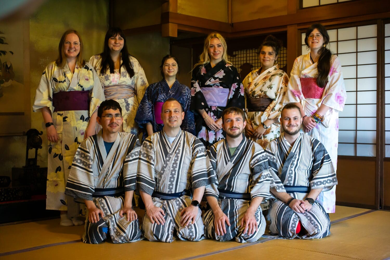 Ten young participants of the Austrian-Japanese youth exchange wear yukatas and pose together in a traditionally furnished Japanese room.